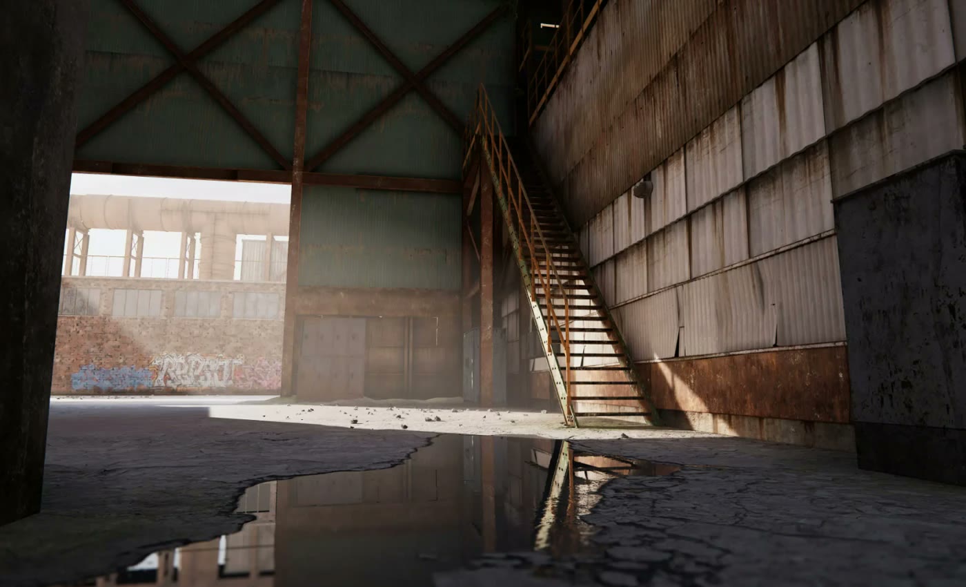 A disused industrial hall with a steel staircase and a puddle on cracked concrete